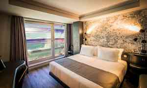 Hotellihuone, jossa on parivuode, flamingokuviollinen tapetti ja ikkuna ulkoseinälle päin. (Tekoälyn luoma teksti)