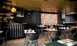 Ravintola, jossa on musta sisustus ja kukkakuvioinen seinä. (Tekoälyn luoma teksti)