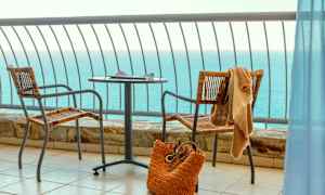 Merinäkymä parvekkeelta, jossa on pöytä, kaksi tuolia ja rantakassi. (Tekoälyn luoma teksti)