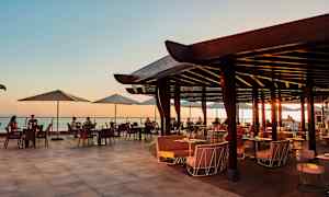 Avoin ravintolaterassi ja näkymä merelle auringonlaskun aikaan. (Tekoälyn luoma teksti)