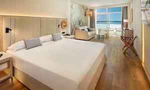 Hotellihuone, jossa on iso sänky, istuinryhmä ja parveke merinäköalalla. (Tekoälyn luoma teksti)