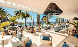 Valoisan loungen sisustus, jossa on modernit huonekalut, suuret ikkunat ja näkymä allasalueelle, palmuihin sekä mereen. (Tekoälyn luoma teksti)