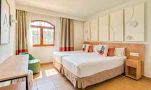 Valoisa ja modernisti sisustettu hotellihuone, jossa on kaksi erillistä vuodetta, ikkunanäkymä ja koristeellisia elementtejä. (Tekoälyn luoma teksti)