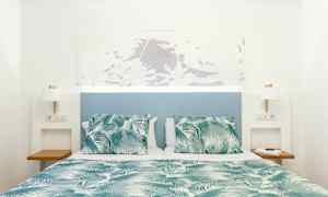 Vuode vihreä-valkoisella kuvioidulla peitolla ja tyynyillä, sininen sängynpääty ja valkoiset seinät. (Tekoälyn luoma teksti)