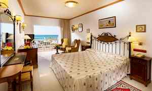 Hotellihuone, jossa on parivuode, istuinryhmä ja parveke merinäköalalla. (Tekoälyn luoma teksti)