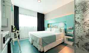 Nykyaikainen hotellihuone, jossa on parivuode, vaaleat värit ja meriteema. (Tekoälyn luoma teksti)