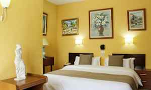 Hotellihuone, jossa on parisänky, koristellut seinät maalauksilla ja pieni patsas huonekalulla. (Tekoälyn luoma teksti)