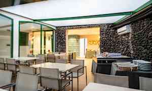 Ruokailutila, jossa on pöytiä ja tuoleja sekä buffet-alue kiviseinän vieressä. (Tekoälyn luoma teksti)