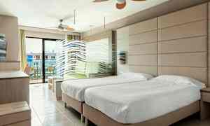 Hotellihuone, jossa on kaksi yhden hengen vuodetta, istuinryhmä ja parveke näkymällä. (Tekoälyn luoma teksti)