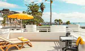 Aurinkotuolit ja pöytä, näkymä merelle ja palmuihin. (Tekoälyn luoma teksti)