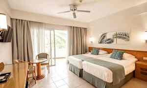 Hotellihuone, jossa kaksi vuodetta, oleskelutila ja parveke. (Tekoälyn luoma teksti)