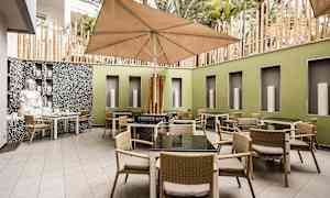 Sisäpiha, jossa pöytiä ja tuoleja sekä suuri varjo. (Tekoälyn luoma teksti)