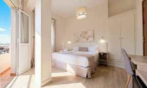 Hotellihuone, jossa on parivuode, yöpöytä, kirjoituspöytä ja vaatekaappi sekä parveke näköalalla. (Tekoälyn luoma teksti)