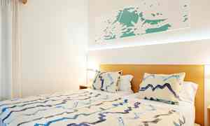 Sänky, jossa kaksi tyynyä ja peitto valoisassa huoneessa. (Tekoälyn luoma teksti)