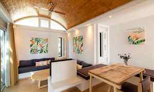 Sisustus, jossa on puupöytä, sohva ja seinäkoristeet kasviaiheilla. (Tekoälyn luoma teksti)