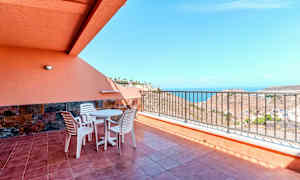 Terassi, jolla on pöytä, tuolit ja kaide sekä merinäköala. (Tekoälyn luoma teksti)