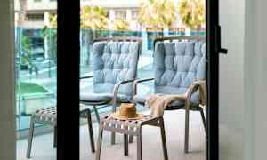 Kaksi sinistä istuintuolia ja yksi jakkara, jossa hattu parvekkeella. (Tekoälyn luoma teksti)