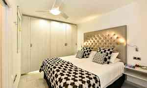 Moderni makuuhuone, jossa parivuode, napitettu sängynpääty ja kuvioidut vuodevaatteet. (Tekoälyn luoma teksti)