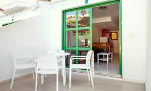 Ulkoterassi, jossa valkoisia kalusteita ja vihreä oviranainen, joka johtaa asuntoon. (Tekoälyn luoma teksti)