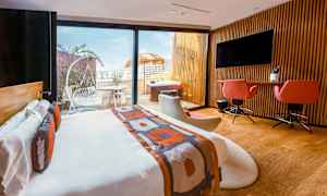 Moderni hotellihuone, jossa parisänky, työpöytä, istuimet sekä pääsy terassille, jossa ulkokalusteet ja poreallas. (Tekoälyn luoma teksti)