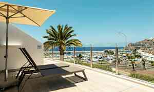 Terassi aurinkotuoleilla ja aurinkovarjolla, näköala venesatamaan ja merelle. (Tekoälyn luoma teksti)