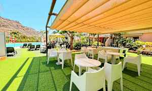 Ulkotila, jossa pöytiä, tuoleja ja lähellä oleva uima-allas. (Tekoälyn luoma teksti)