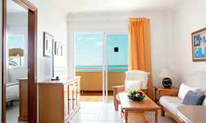 Olohuone, jossa sohva, pöytä ja näkymä merelle lasioven kautta. (Tekoälyn luoma teksti)