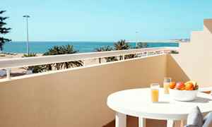 Parveke näköalalla merelle, pöytä hedelmäkulholla ja lasillinen mehua. (Tekoälyn luoma teksti)