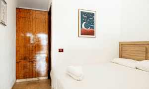 Pieni huone, jossa on puusänky ja valkoiset vuodevaatteet. Seinällä on kuvituskuva kuusta. (Tekoälyn luoma teksti)