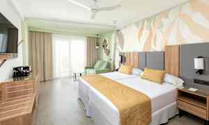 Hotellihuone, jossa on kaksi sänkyä, sohva ja koristeellinen seinäsuunnittelu. (Tekoälyn luoma teksti)