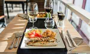 Lautasella on kalaa, vihanneksia ja perunaa sekä lasillinen valkoviiniä. (Tekoälyn luoma teksti)