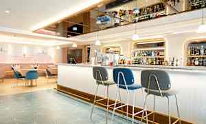 Moderni hotellibaari, jossa istumapaikkoja ja pulloja hyllyillä. (Tekoälyn luoma teksti)