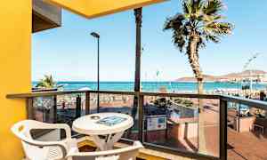 Näkymä parvekkeelta, jossa pöytä ja tuolit, merelle ja rannalle. (Tekoälyn luoma teksti)