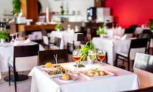 Katettu pöytä ravintolassa, jossa on ruokaa ja juomia. (Tekoälyn luoma teksti)