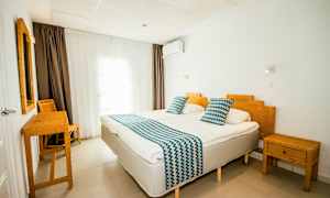 Hotellihuone, jossa kaksi yhden hengen vuodetta, bambukalusteet ja valkoiset seinät. (Tekoälyn luoma teksti)