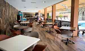 Tilava ulkoilmaravintola, jossa on pöytiä ja tuoleja altaan vieressä. (Tekoälyn luoma teksti)