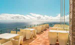 Terassi, jossa pöytiä ja tuoleja meren äärellä. (Tekoälyn luoma teksti)