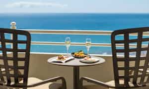 Kaksi lautasta ruokaa ja kaksi juomalasia pöydällä, merinäköala taustalla. (Tekoälyn luoma teksti)