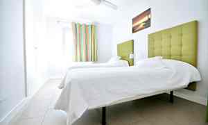 Huone, jossa on kaksi vihreällä verhoillulla päätyllä varustettua yhden hengen vuodetta. (Tekoälyn luoma teksti)