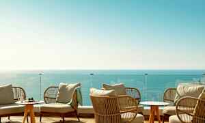 Loungealue, jossa istumakalusteita, lasikaide ja näkymä merelle. (Tekoälyn luoma teksti)