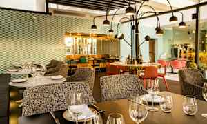 Moderni ravintola, jossa katetut pöydät, tuolit ja koristeellinen valaistus. (Tekoälyn luoma teksti)