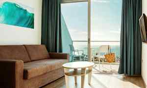 Olohuone, jossa on sohva ja pöytä, parveke ja näkymä merelle. (Tekoälyn luoma teksti)