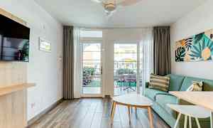 Valoisa oleskelutila, jossa vihreä sohva, sohvapöytä ja näkymä terassille lasioven kautta. (Tekoälyn luoma teksti)