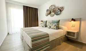 Makuuhuone, jossa on parivuode, koristeelliset tyynyt ja koristeltu pääty. (Tekoälyn luoma teksti)