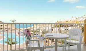 Näkymä parvekkeelta, jossa on valkoiset kalusteet, kohti uima-allasta ja merinäköalaa. (Tekoälyn luoma teksti)