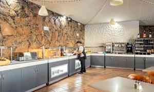 Aamiaispöytä ravintolassa, jossa on kiviseinä ja nykyaikaiset palvelut. (Tekoälyn luoma teksti)