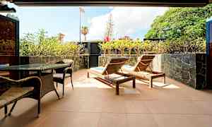 Terassi, jossa on aurinkotuoleja, pöytä ja tuoleja, ympärillä kasveja. (Tekoälyn luoma teksti)