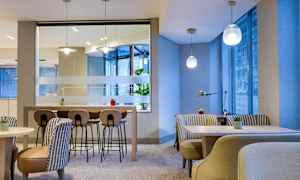 Modernisti sisustettu kahvilaympäristö, jossa pöytiä, tuoleja ja kasveja. (Tekoälyn luoma teksti)