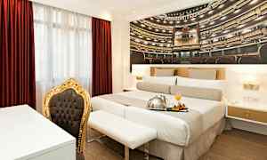 Huone, jossa parivuode, punainen verho ja kultakehysinen tuoli. (Tekoälyn luoma teksti)