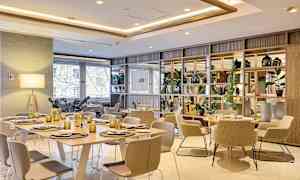 Modernisti sisustettu ruokailutila, jossa on pöytiä, tuoleja ja koristeellisia yksityiskohtia. (Tekoälyn luoma teksti)